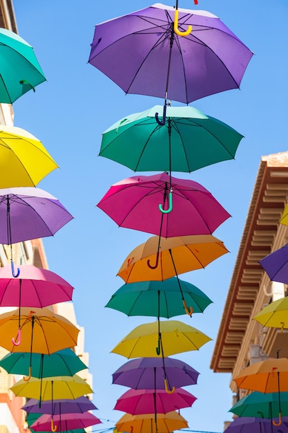 Foto straat met felle veelkleurige parasols tegen de lucht met huizen