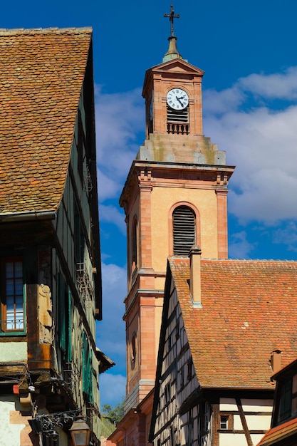 Straat met traditionele halfhouten huizen en klokkentoren in de middeleeuwse stad Riquewihr