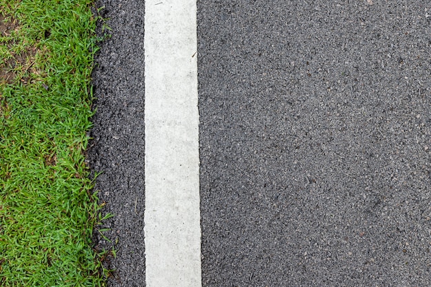 Straat van het oppervlakte grunge de ruwe asfalt zwarte donkergrijze weg en groene grastextuur