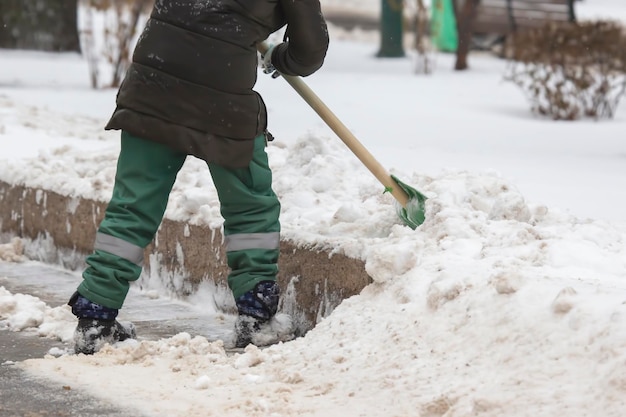 Straathoekwerker schept sneeuw van de stoep