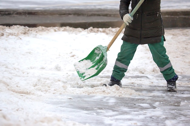 Straathoekwerker schept sneeuw van het trottoir