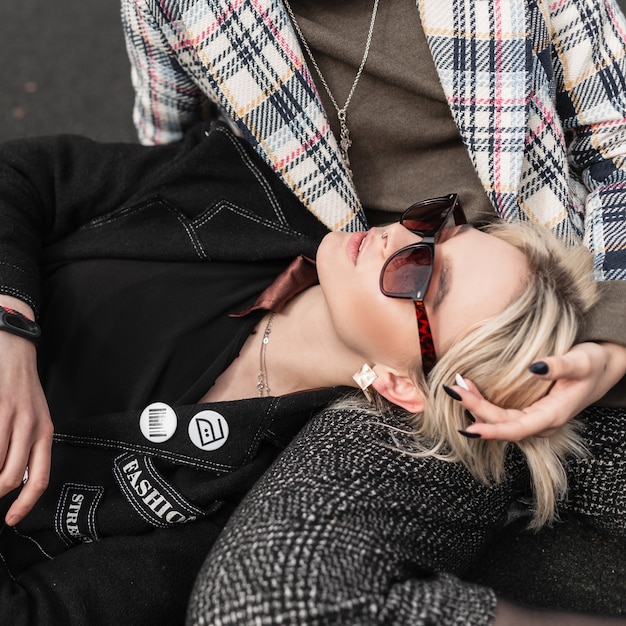 Straatportret aantrekkelijke blonde vrouw in modieuze zwarte blazer in stijlvolle zonnebril