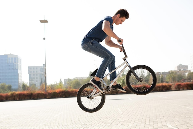 Straatportret van een bmx-rijder in een sprong op straat op de achtergrond van het stadslandschap