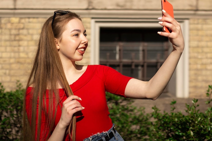 Foto straatportret van een jonge vrouw in rode kleren die een inhoud voor sociale media maakt
