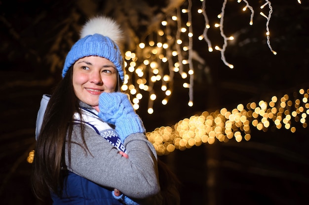 Straatportret van glimlachende mooie jonge vrouw op de feestelijke Kerstmismarkt