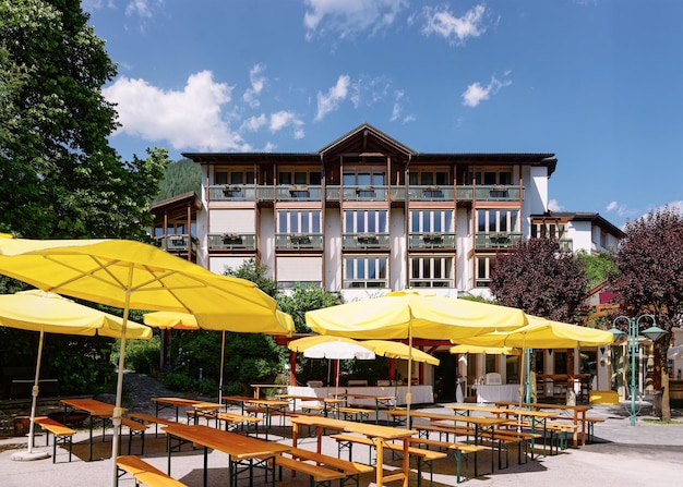Straatrestaurant met parasols, tafels en stoelen in hotel en familieresort in Bad Kleinkirchheim in Karinthië, Oostenrijk. Sidewalk café terras en architectuur van het gebouw met buiten. levensstijl