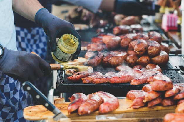 Straatvoedsel in amsterdam op zondagmarkt de kok maakt tosti's met gebakken worstjes en mosterd