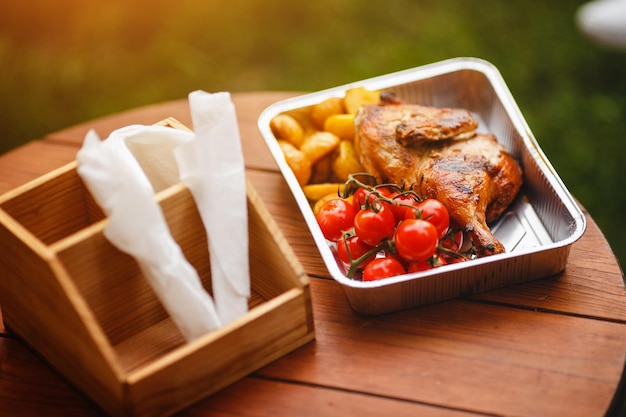 Straatvoedsel Kippendij met gouden korst en aardappelen gesneden op een bord met verse tomaten