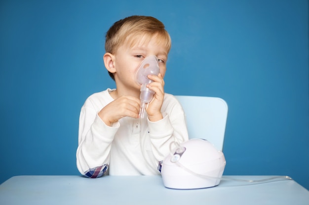 strabismus boy doing inhalation with a nebulizer on a blue