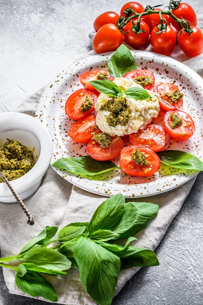 Stracciatella on small plate served with fresh tomatoes and basil.