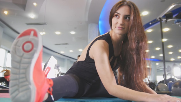 Straching in the gym - young woman exercising healthy lifestyle in fitness studio, close up