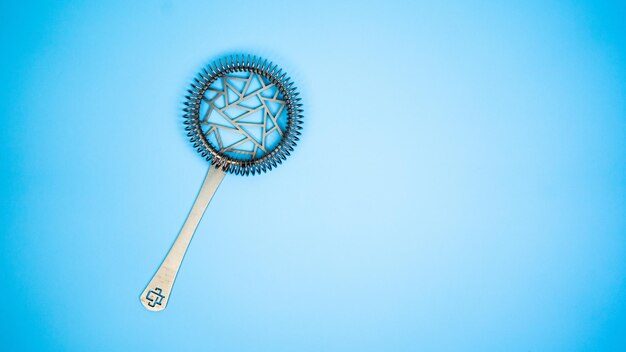 A strainer on a bright blue background