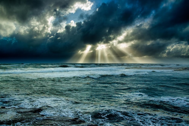 Stralen van zonlicht over stormzeeën en donkere regenwolken