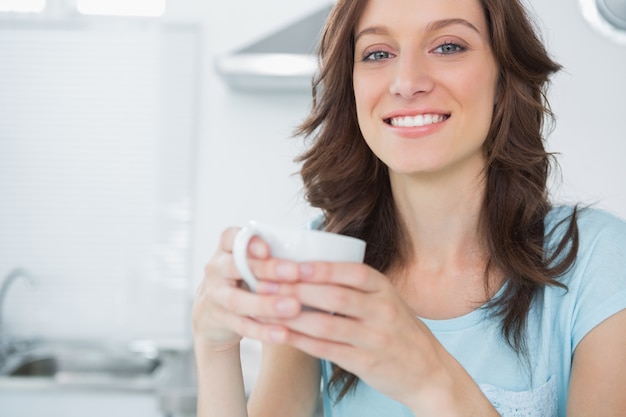 Stralende brunette die koffie drinkt