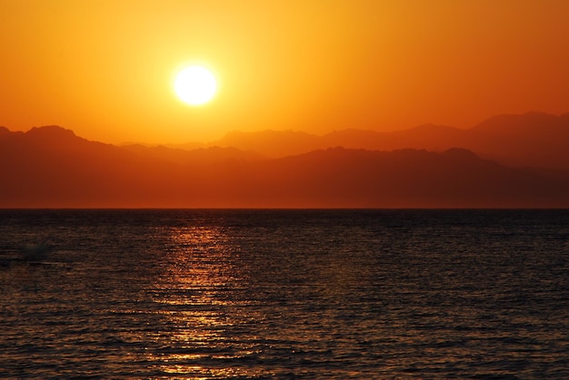 Stralende warme zonsopgang op de zee met bergen links