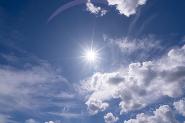 Stralende zon op heldere blauwe hemel witte wolken met lens flare van zonlicht op hemelachtergrond Felle zon op blauwe hemel Concept Natuur en milieu achtergrond