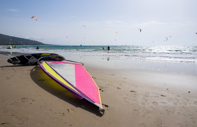 Strand aan de kust van licht Bord met zijn zeil wachtend op windsurfen onherkenbaar kitesurfen