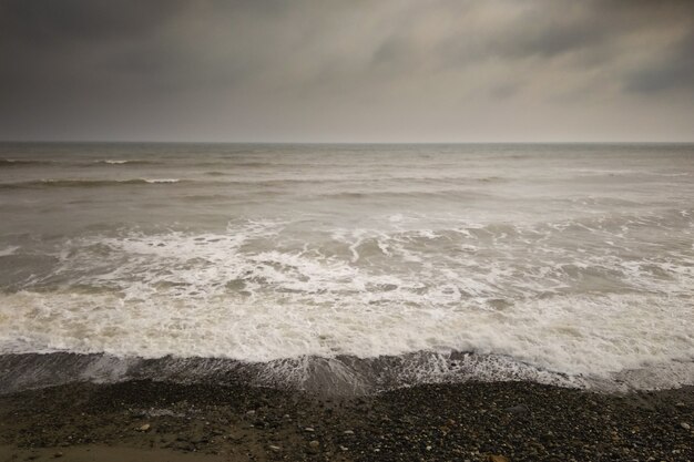 Strand met donkere wolken na stormlandschap