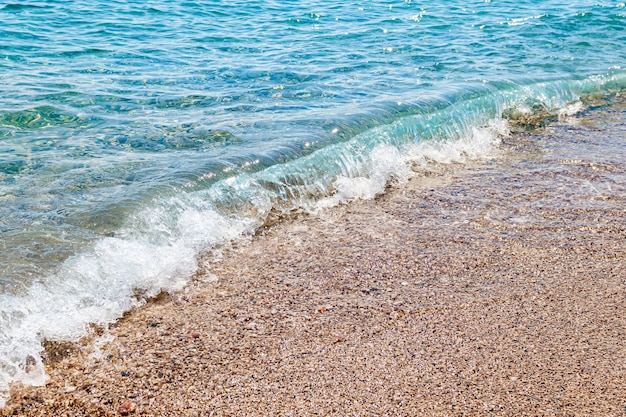 Strand met kleine steentjes en helder water