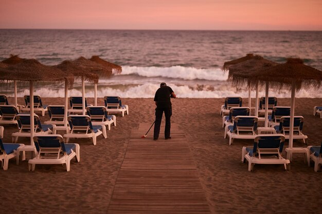 Strand met ligstoelen in Spain.A man veegt een pad op het strand in de badplaats Marbella, Spanje.