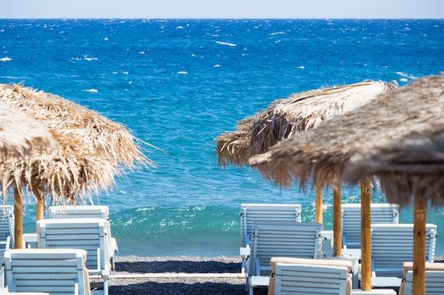 Strand met parasols en ligstoelen aan zee in Santorini