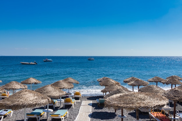 Strand met parasols en ligstoelen aan zee in Santorini