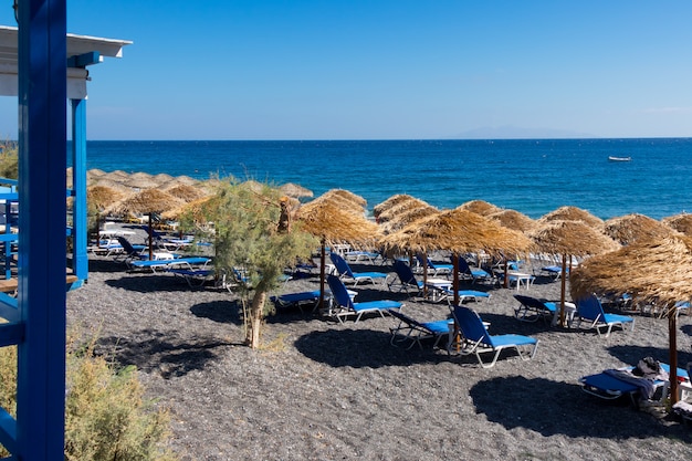 Strand met parasols en ligstoelen aan zee in Santorini