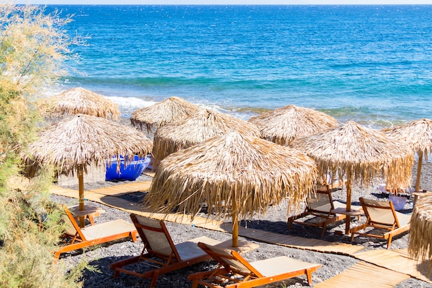 Strand met parasols en ligstoelen aan zee in Santorini