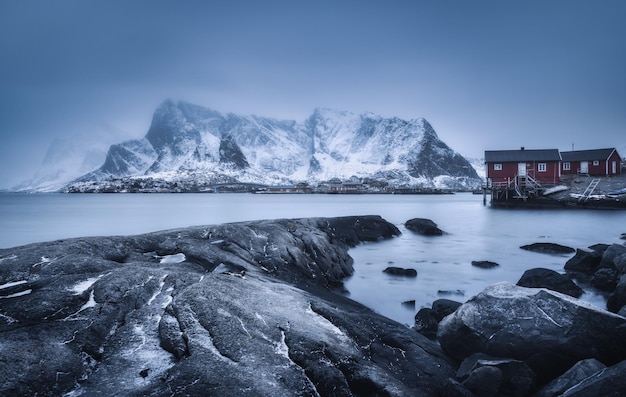 Foto strand met stenen in wazig water rode rorbu en besneeuwde bergen