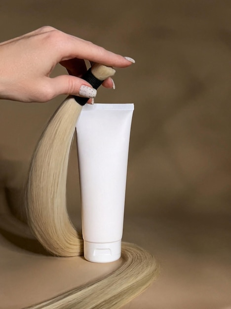 A strand of natural light hair for extensions with a bottle of care product