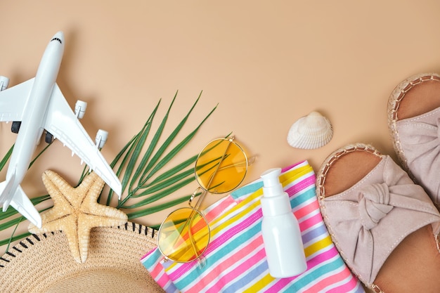 Strand rieten stro, fel gestreepte jurk, spf crème, sandalen groen tropisch blad en gele zonnebril op zand