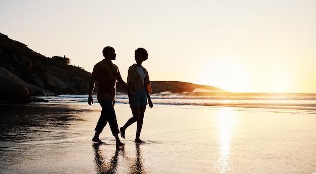 Strand zonsondergang en silhouet paar lopen op zand hand in hand en genieten van romantische tijd samen