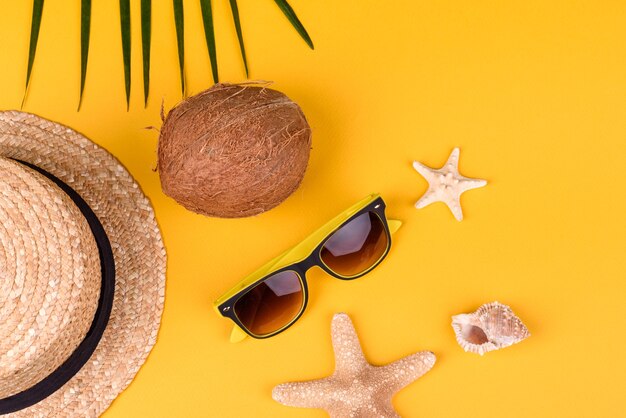 Strandaccessoires: bril en hoed met schelpen en zeesterren op een gekleurde achtergrond. Zomer achtergrond