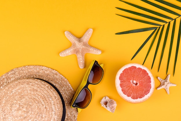 Strandaccessoires: bril en hoed met schelpen en zeesterren op een gekleurde achtergrond. Zomer achtergrond