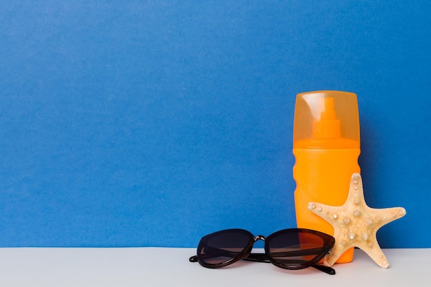 Strandaccessoires moisturizer zonnebrandcrème zonnebrandcrème fles voor uvb-huidverzorgingsbescherming in de zomer met schelpen op gekleurde achtergrond mock up met kopieerruimte