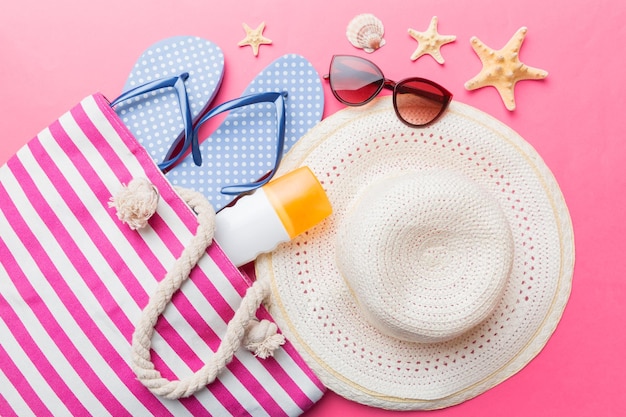 Strandaccessoires plat lag bovenaanzicht op gekleurde achtergrond Zomerreisconcept Tas met zeester en zeeschelp Bovenaanzicht