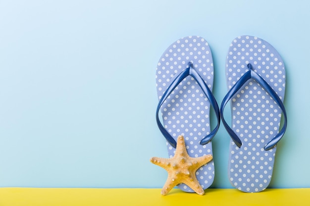 Strandaccessoires Slippers en zeesterren op gekleurde achtergrond Mock up met kopieerruimte