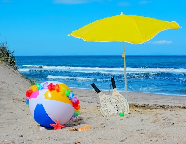 Strandbal met ketting rackets en parasol aan zee