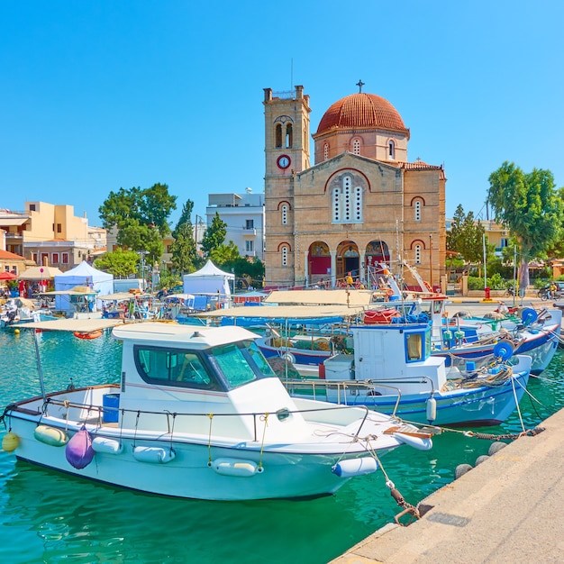 Strandboulevard met Ekklisia Isodia Theotokou-kerk in Aegina-stad en afgemeerde vissersboten, Aegina-eiland, Griekenland