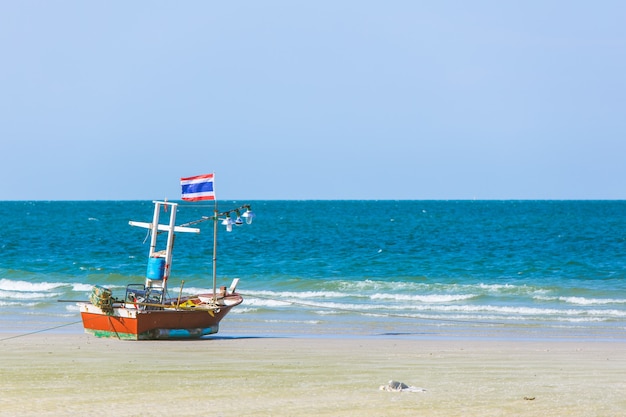 A stranded boat with Thai flag on the beach