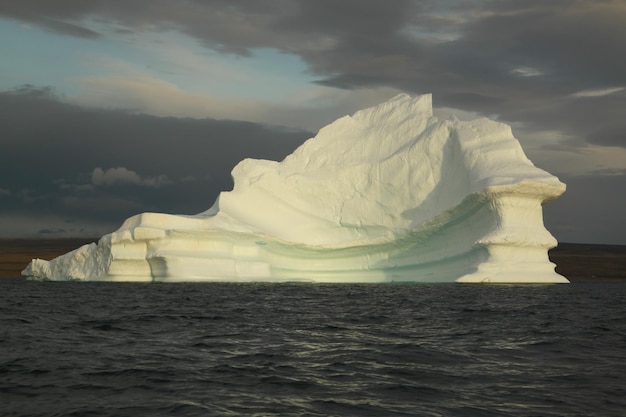 Выброшенный на мель столовый айсберг и лед ближе к вечеру в арктическом ландшафте, недалеко от залива Понд, Нунавут