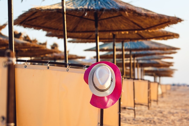 Strandhoed die tussen parasols hangt.