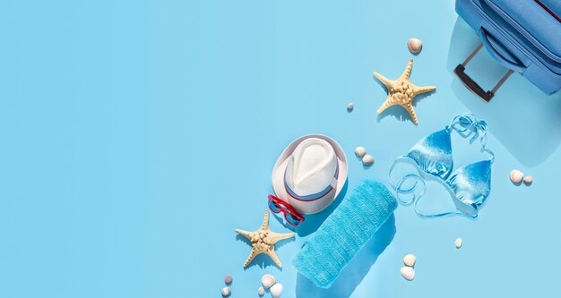 Strandhoed, koffer, zonnebril, handdoek, zeester, schelpen voor vrouwen op reis.