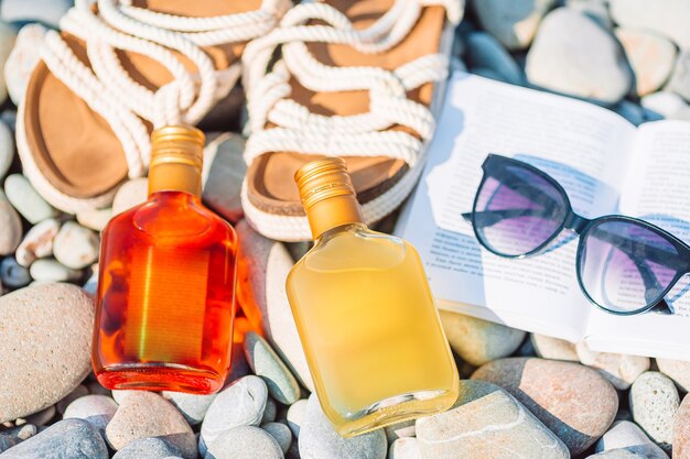 Strandhoed op geopend boek met zonnebrandcrème en schoenen op kiezelstrand