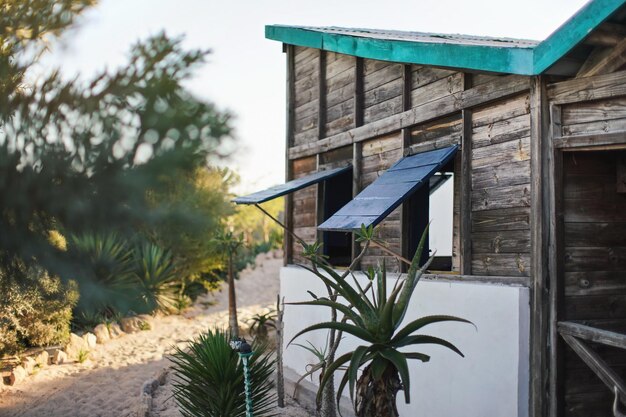 Strandhuis met helder aquakleurig dak, houten ramen geopend, zandpad naar zee op de achtergrond. Tropisch eiland strandresort.