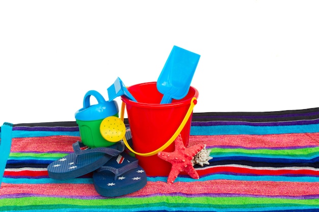 Strandspeelgoed met slippers op handdoek geïsoleerd op witte achtergrond