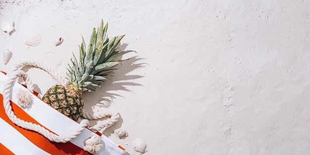 Strandtas in witte en rode strepen op het zand ananas steekt uit de tas