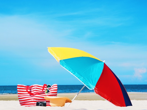 Strandtas met kleurrijke paraplu op mooie strandachtergrond.