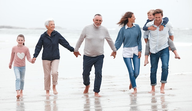 Strandwandeling en grote familie aan het sporten tijdens een vakantie in Australië tijdens de zomer in het water Gelukkige grootouders ouders en kinderen op gezondheidswandeling buiten tijdens een avontuurlijke reis of vakantie
