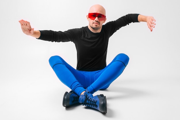 Strange man in stylish clothes and red sunglasses posing in white studio